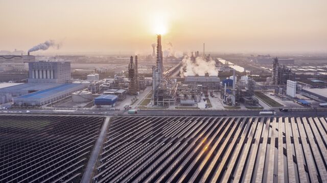 Industrielt kompleks med olieraffinaderi og solcelleanlæg ved solopgang